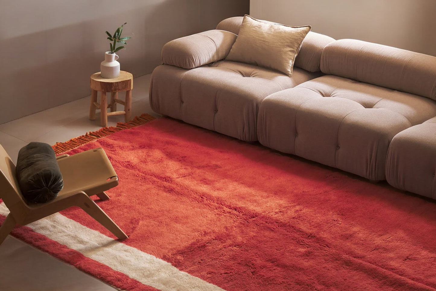 A minimalist Moroccan rug in deep red with subtle cream accents and tassel fringes on the edge. This natural wool rug adds warmth and style to any room and is customizable to fit various spaces.
