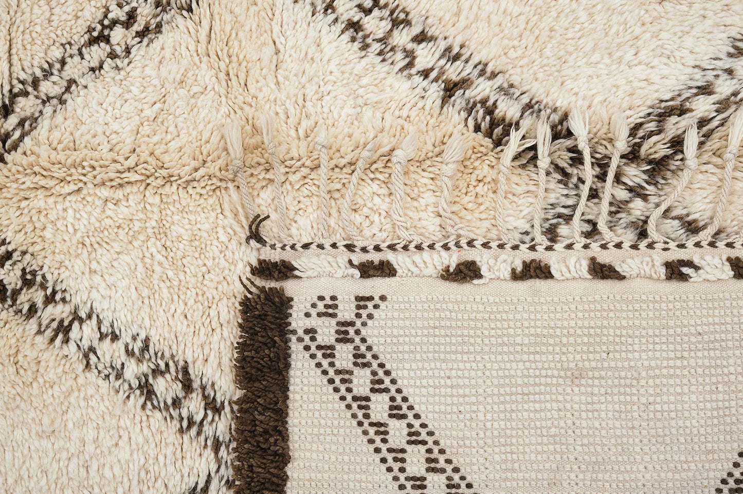 A traditional Moroccan shag rug in cream with a bold brown diamond pattern and tasseled edges, made from natural wool. This rug adds warmth and Moroccan charm to any space and is available in custom sizes.