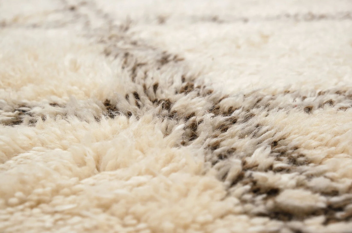 A traditional Moroccan shag rug in cream with a bold brown diamond pattern and tasseled edges, made from natural wool. This rug adds warmth and Moroccan charm to any space and is available in custom sizes.