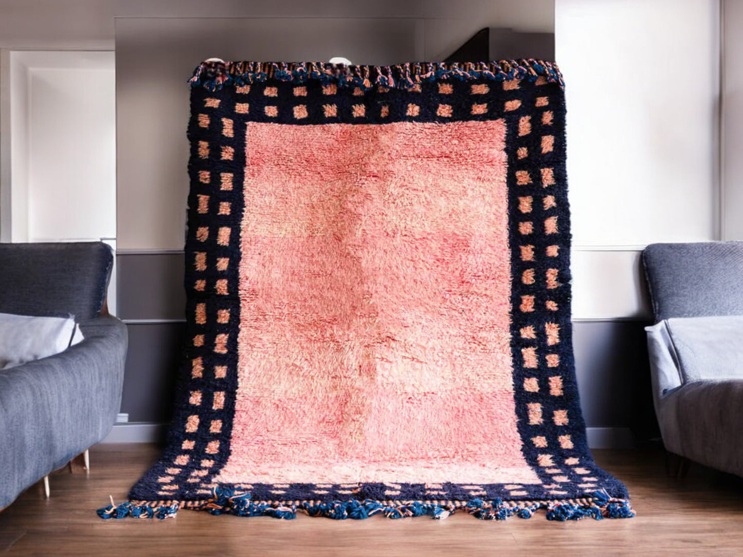 Handmade Moroccan wool rug featuring a vibrant pink center with a navy checkered border and fringed edges, creating a bold and stylish look for modern, boho, or eclectic interiors