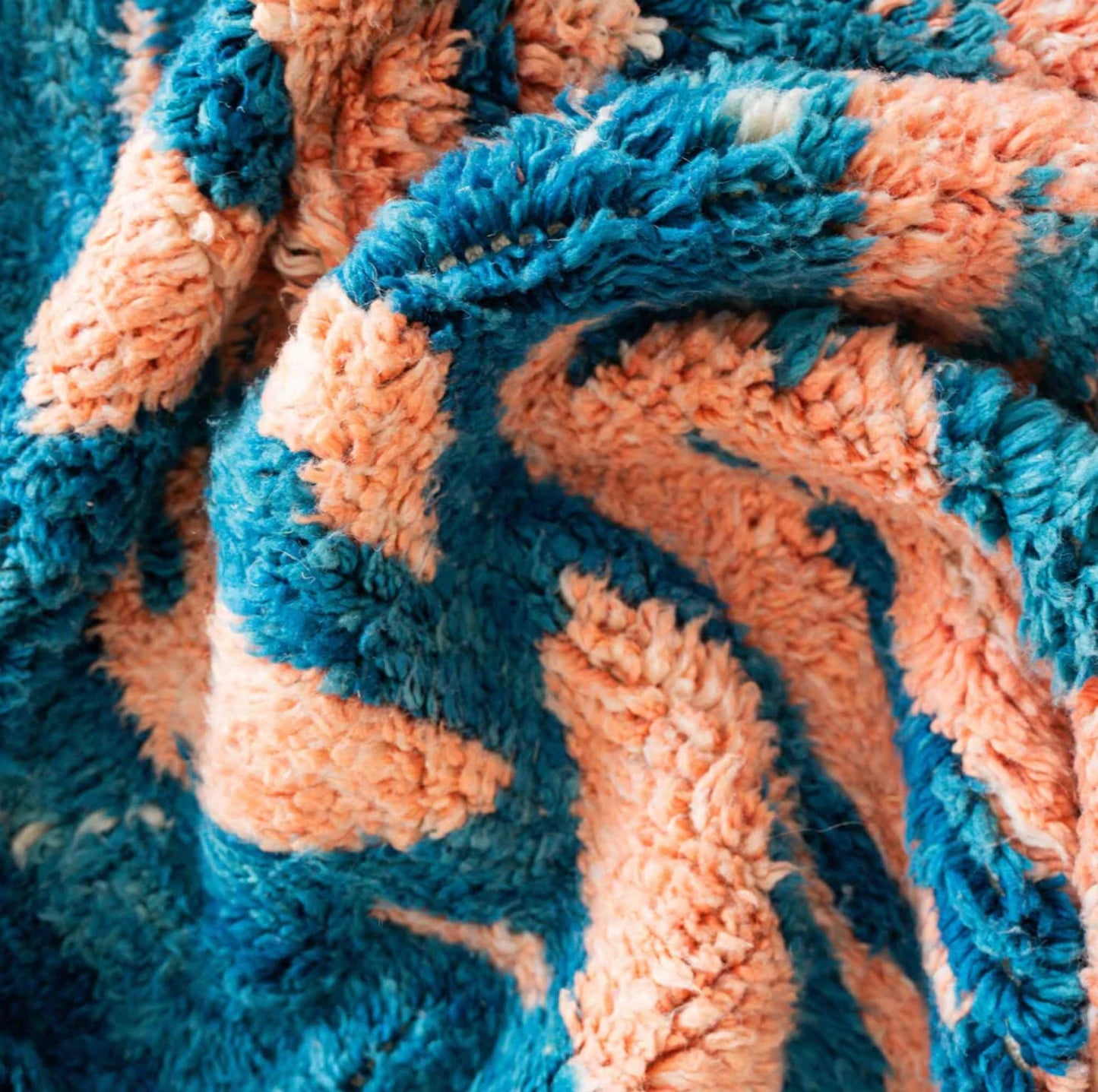 Handmade Moroccan wool rug featuring an ocean-inspired abstract pattern with vibrant blue and pink tones, accented by fringed edges, creating a bold and serene piece for modern or coastal interiors