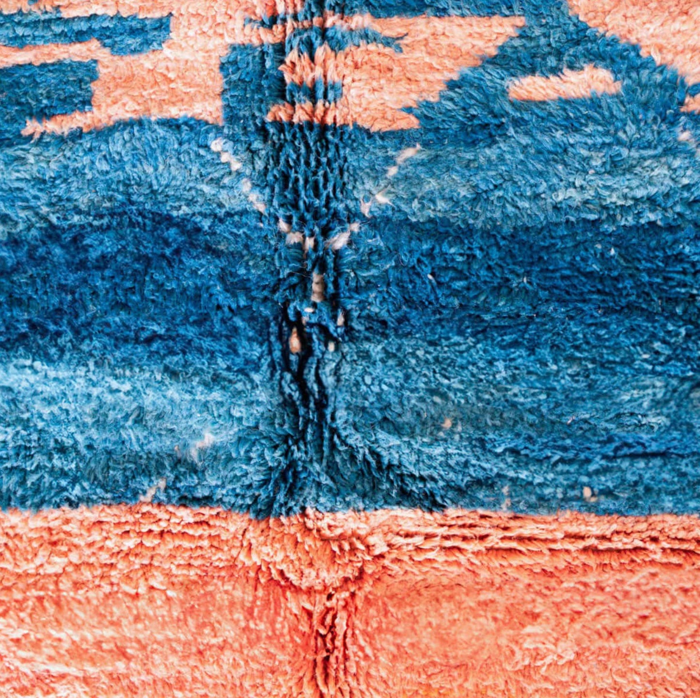 Handmade Moroccan wool rug featuring an ocean-inspired abstract pattern with vibrant blue and pink tones, accented by fringed edges, creating a bold and serene piece for modern or coastal interiors