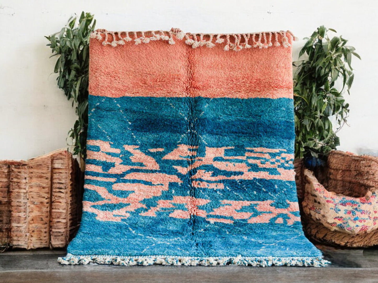 Handmade Moroccan wool rug featuring an ocean-inspired abstract pattern with vibrant blue and pink tones, accented by fringed edges, creating a bold and serene piece for modern or coastal interiors