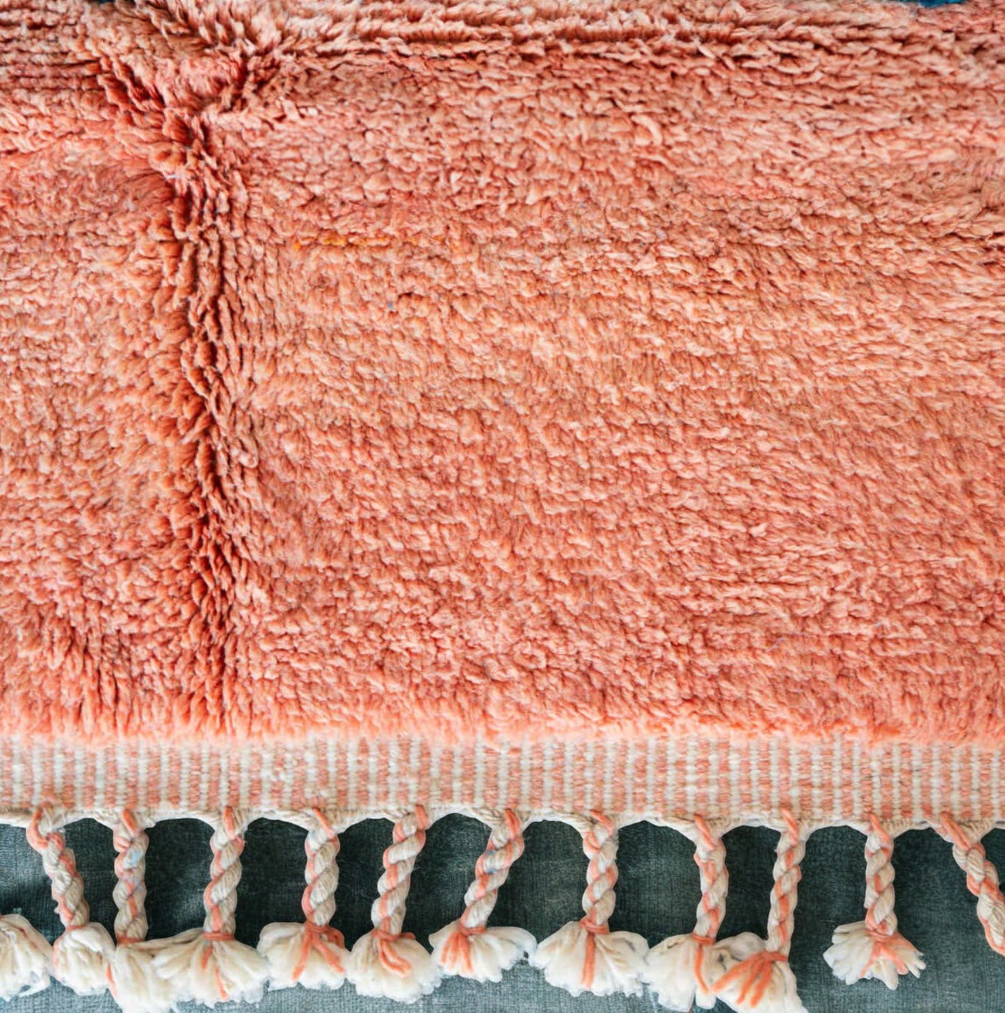 Handmade Moroccan wool rug featuring an ocean-inspired abstract pattern with vibrant blue and pink tones, accented by fringed edges, creating a bold and serene piece for modern or coastal interiors