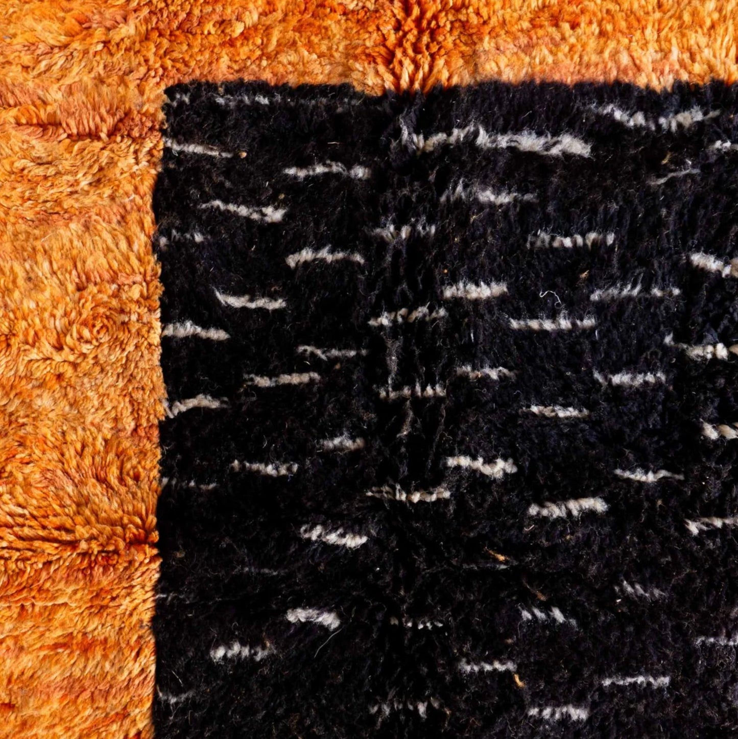 Handmade Moroccan wool rug with a bold orange base and black geometric patterns, ideal for modern, eclectic, or industrial interiors, featuring a contemporary design with sleek lines