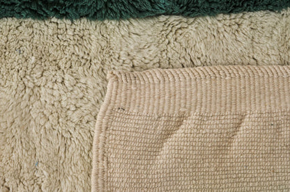 A modern Moroccan rug with bold green geometric stripes on a cream wool base, blending minimalist design and craftsmanship. Handcrafted and available in custom sizes for contemporary interiors.
