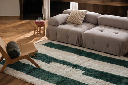 A modern Moroccan rug with bold green geometric stripes on a cream wool base, blending minimalist design and craftsmanship. Handcrafted and available in custom sizes for contemporary interiors.
