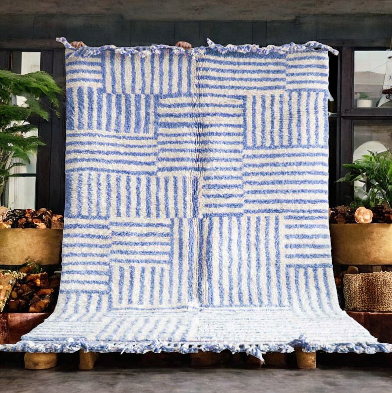 Artisanal handmade wool rug in a sky blue and white striped patchwork design, accented by delicate fringe, displayed on a natural wooden floor, ideal for coastal and modern decor.