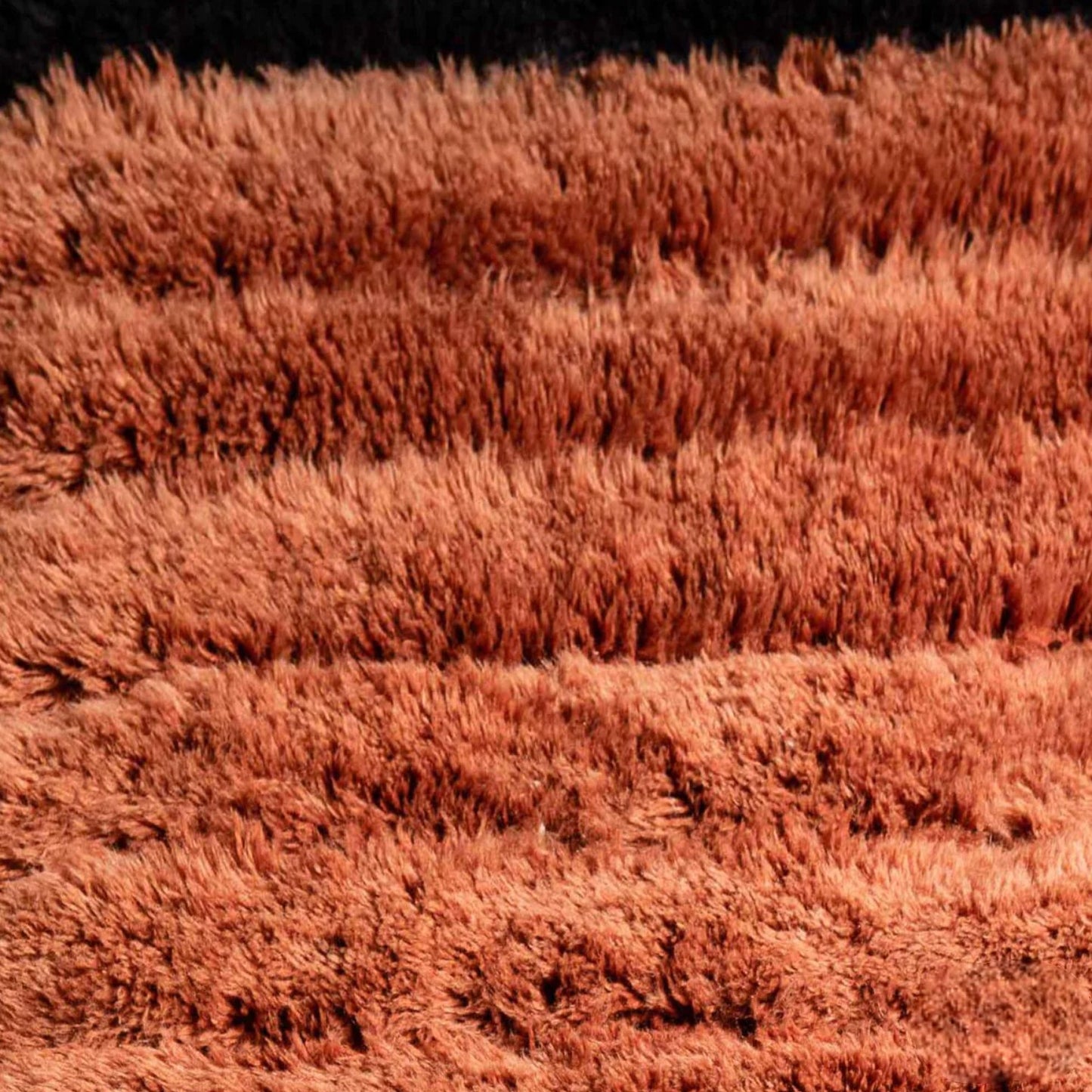 Handmade wool rug with bold horizontal stripes in deep black and terracotta orange, showcasing a sleek ribbed texture, ideal for modern and minimalist decor styles.