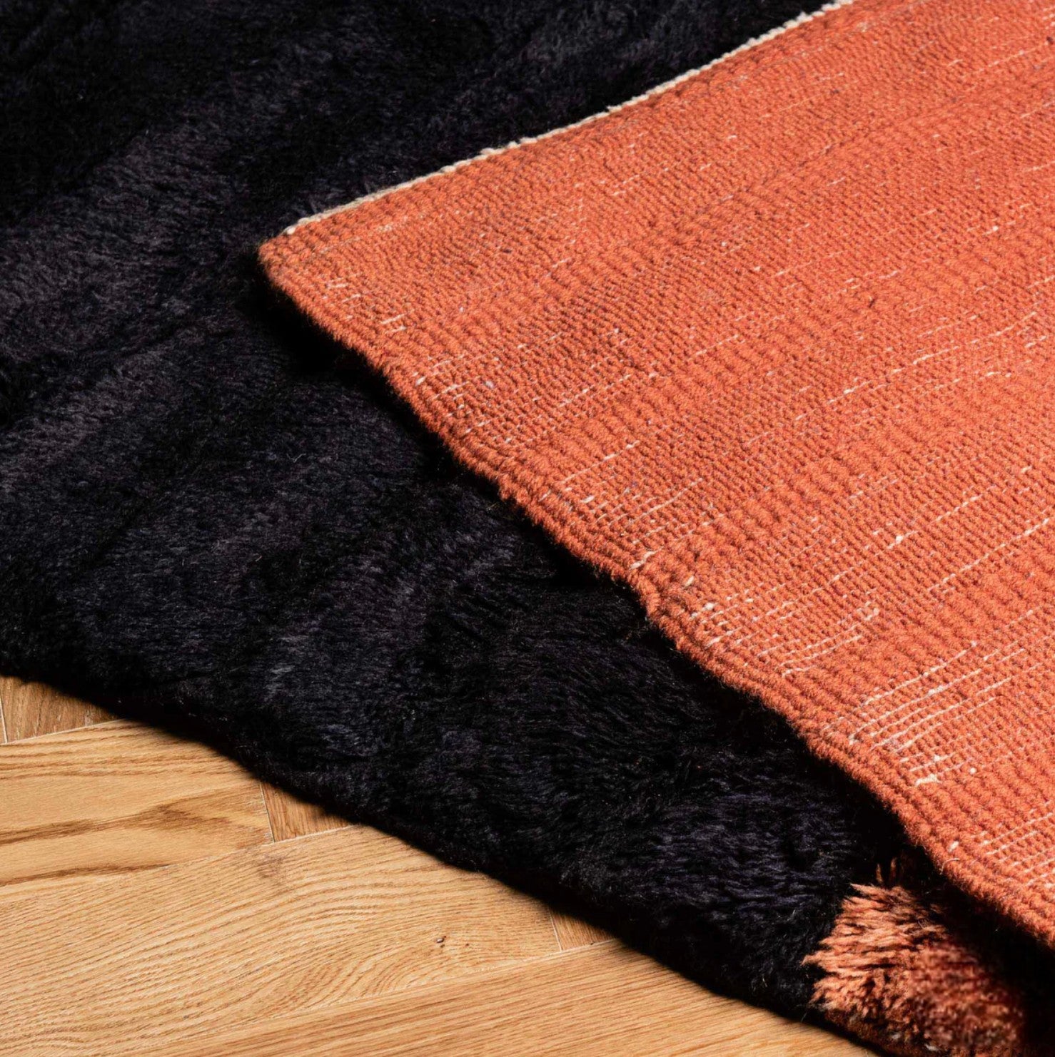 Handmade wool rug with bold horizontal stripes in deep black and terracotta orange, showcasing a sleek ribbed texture, ideal for modern and minimalist decor styles.