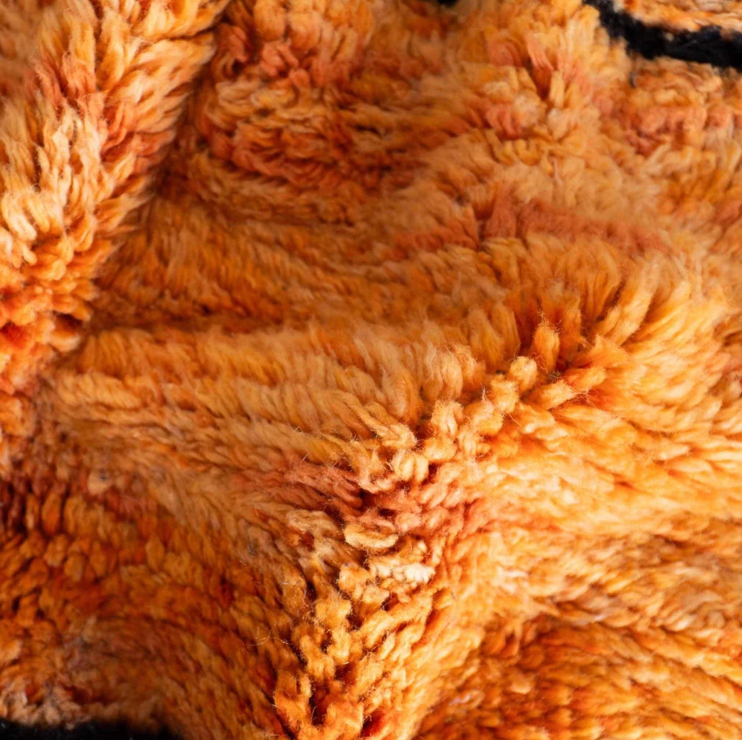 Handmade wool rug with bold black abstract shapes and linear patterns on a vibrant orange background, crafted with intricate texture and detailing, ideal for statement modern or eclectic decor.