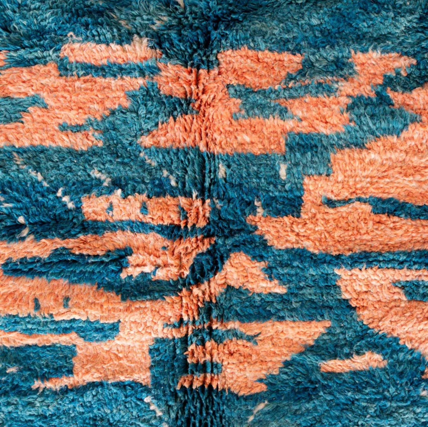Handmade Moroccan wool rug featuring an ocean-inspired abstract pattern with vibrant blue and pink tones, accented by fringed edges, creating a bold and serene piece for modern or coastal interiors
