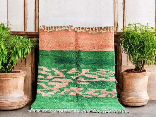Handmade Moroccan wool rug featuring a lush green base with soft peach abstract patterns and fringed edges, perfect for boho, modern, or eclectic interiors

