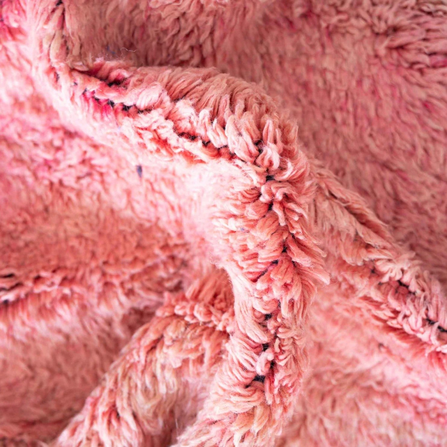 Handmade Moroccan wool rug featuring a vibrant pink center with a navy checkered border and fringed edges, creating a bold and stylish look for modern, boho, or eclectic interiors
