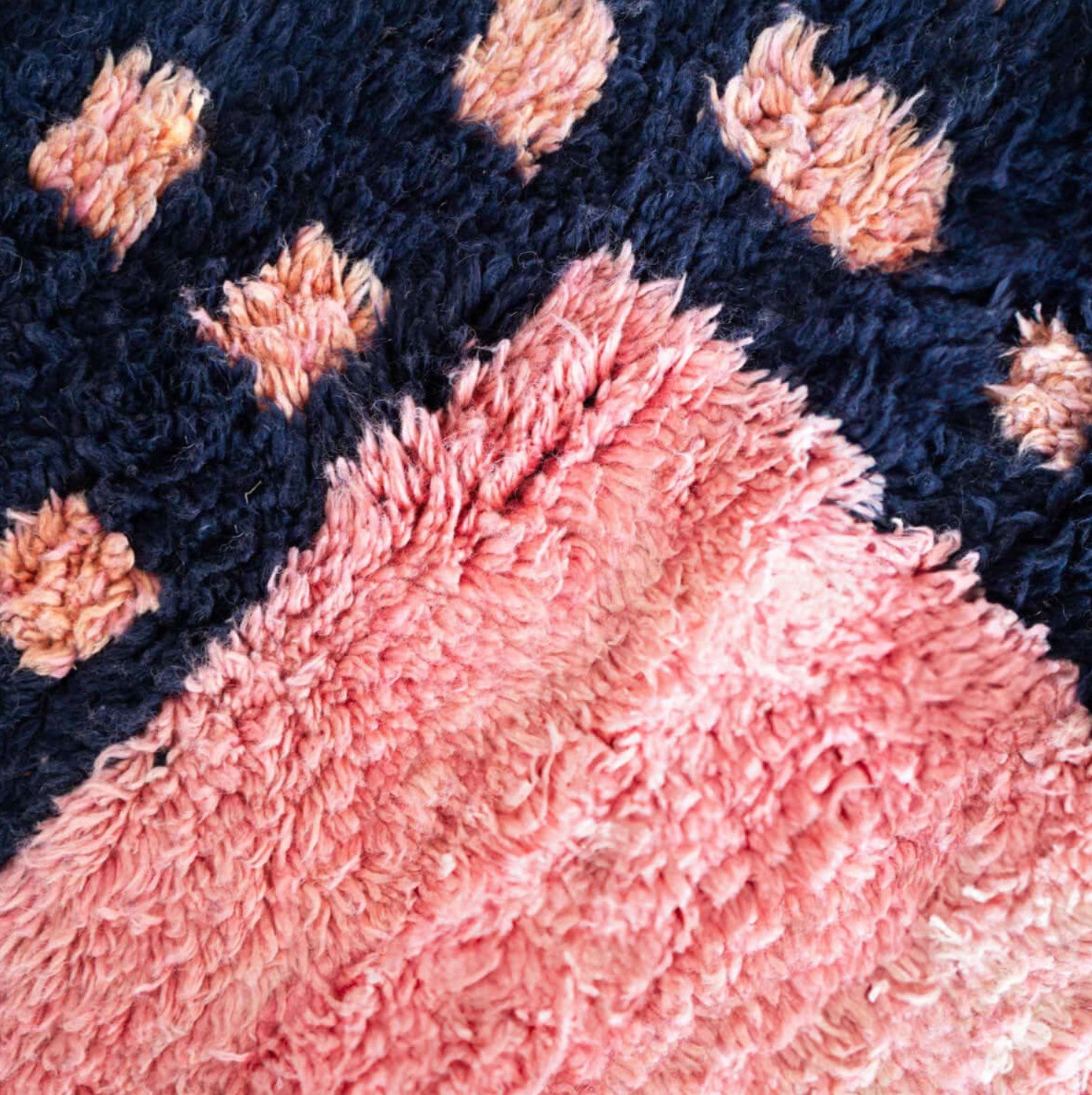 Handmade Moroccan wool rug featuring a vibrant pink center with a navy checkered border and fringed edges, creating a bold and stylish look for modern, boho, or eclectic interiors
