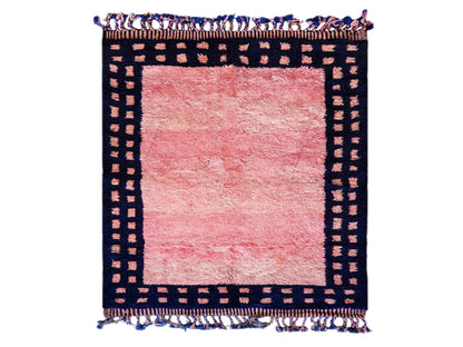 Handmade Moroccan wool rug featuring a vibrant pink center with a navy checkered border and fringed edges, creating a bold and stylish look for modern, boho, or eclectic interiors
