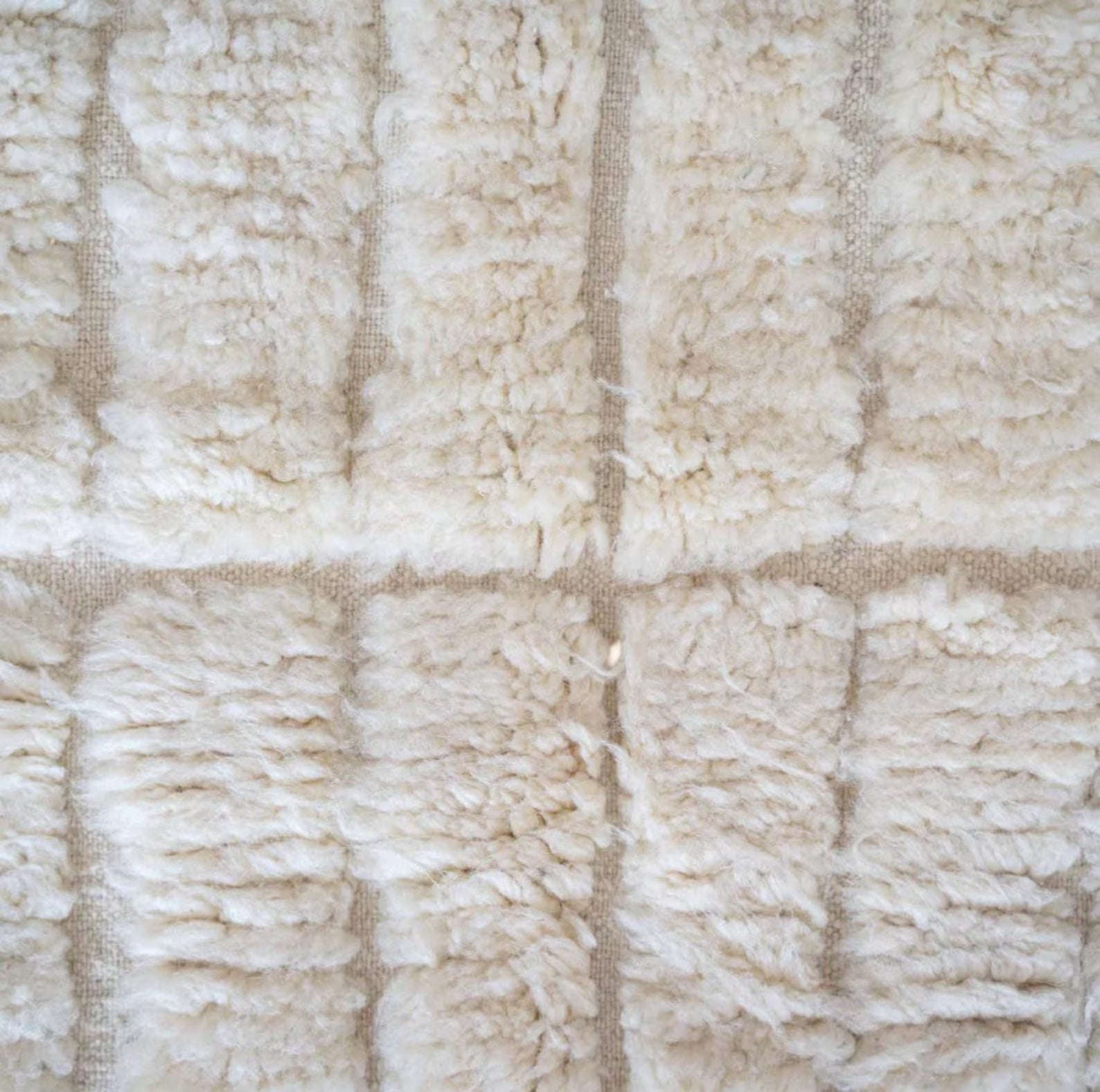 This handmade Moroccan rug features a luxurious cream white wool texture with a minimalist grid pattern. Ethically handwoven by Berber women in the High Atlas Mountains, it brings softness, warmth, and authenticity to any living room, bedroom, or serene corner. Perfect for Japandi, boho, minimalist, or modern interiors. Crafted from 100% natural wool with exquisite care. Custom sizing available for your space.