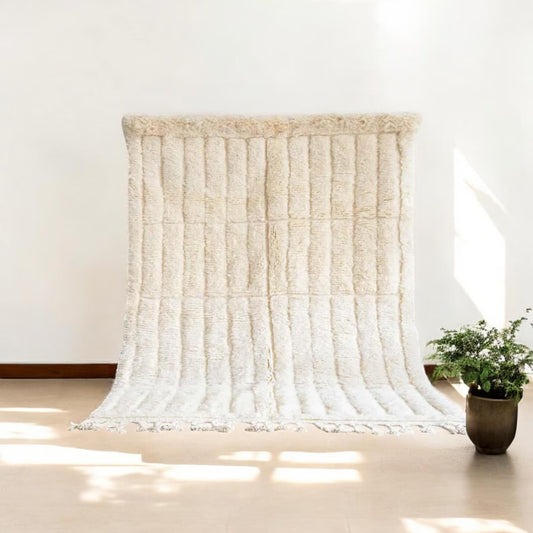 This handmade Moroccan rug features a luxurious cream white wool texture with a minimalist grid pattern. Ethically handwoven by Berber women in the High Atlas Mountains, it brings softness, warmth, and authenticity to any living room, bedroom, or serene corner. Perfect for Japandi, boho, minimalist, or modern interiors. Crafted from 100% natural wool with exquisite care. Custom sizing available for your space.